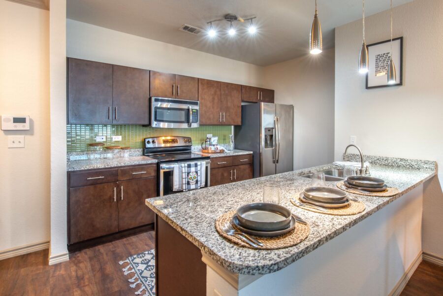 Close-up view of apartment kitchen with stainless steel appliances and granite counters